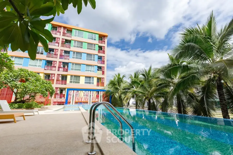 Stunning poolside view with modern apartment building and lush palm trees under a clear blue sky.