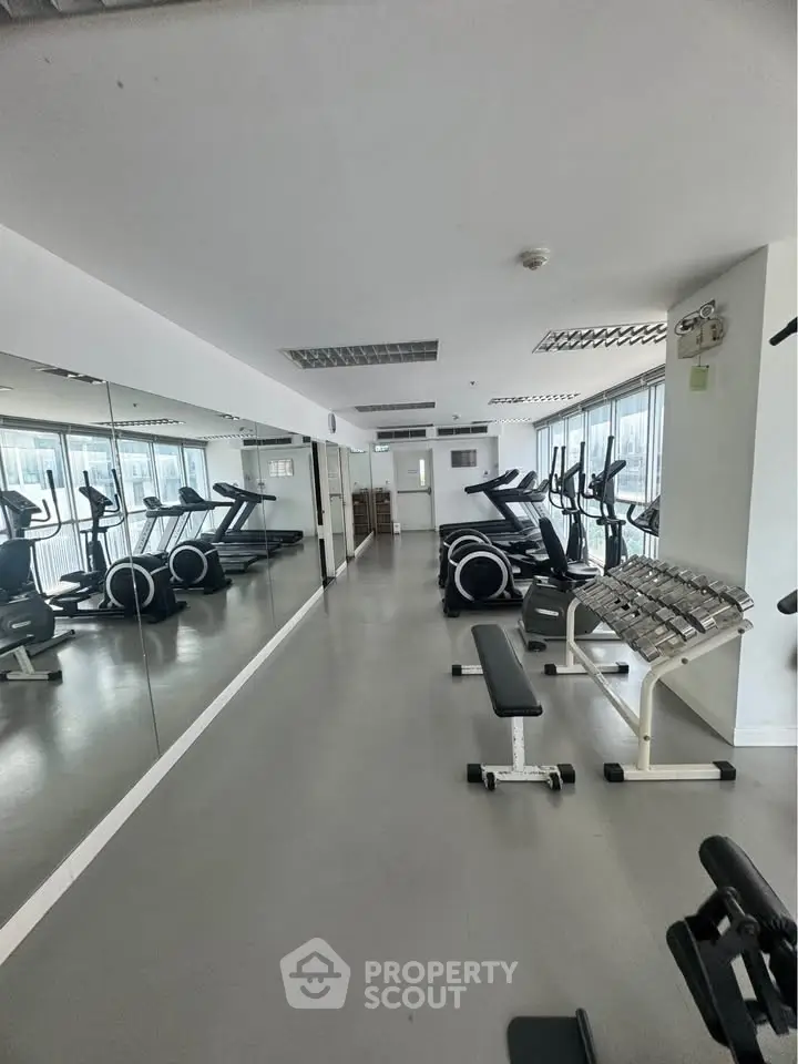 Modern gym with state-of-the-art equipment and mirrored walls in a residential building.