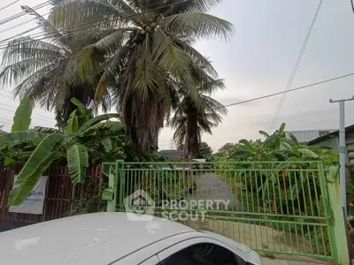 Charming tropical property entrance with lush greenery and secure gate access.