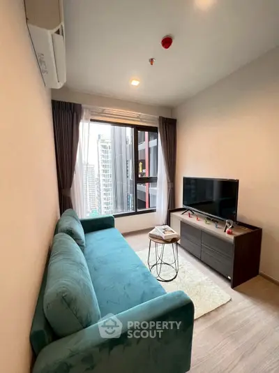 Modern living room with city view, featuring a plush teal sofa and sleek entertainment unit.