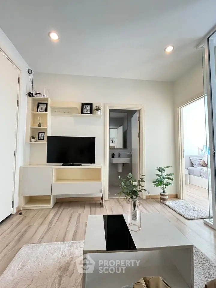Modern living room with sleek furniture and open layout, featuring a TV and stylish decor.