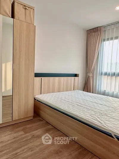 Modern bedroom with wooden furniture and large window for natural light.