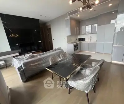 Modern open-layout living room with sleek kitchen and dining area, featuring stylish furniture and contemporary design.