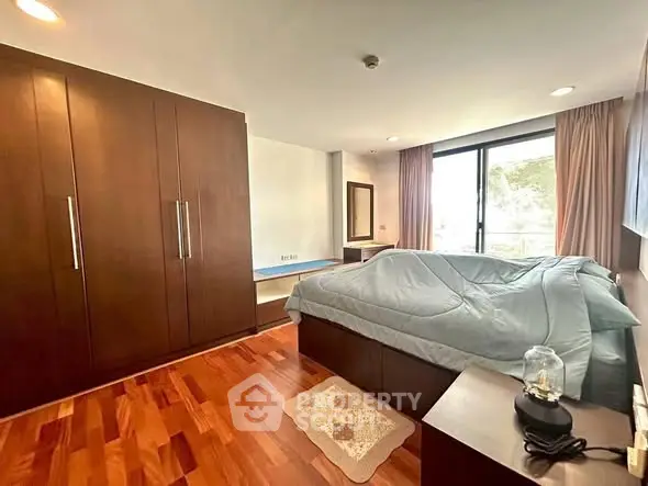 Spacious bedroom with wooden flooring and large wardrobe in modern apartment