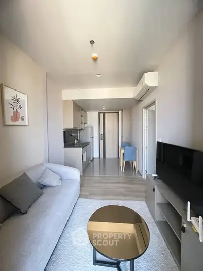 Modern living room with sleek furniture and open kitchen layout in a stylish apartment.