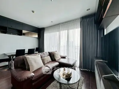 Modern living room with leather sofa and large windows offering city views.