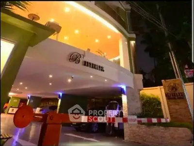 Elegant building entrance with modern lighting and secure parking area at night.