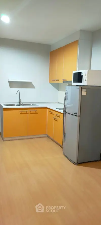Modern kitchen with vibrant orange cabinets and stainless steel appliances