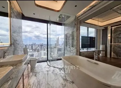 Luxurious bathroom with marble finishes and stunning city view from floor-to-ceiling windows.