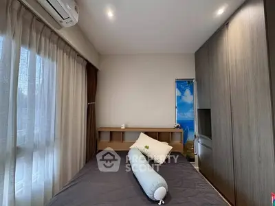 Cozy bedroom with modern design, featuring a large wardrobe and natural light from a window.