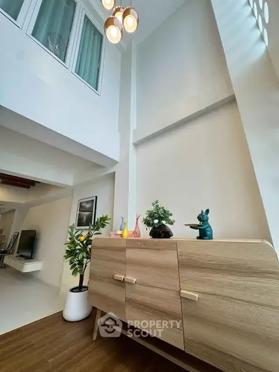 Modern living room with stylish wooden cabinet and decorative accents in a bright, airy space.