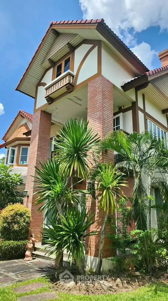 Charming two-story brick house with lush garden and elegant architectural details.