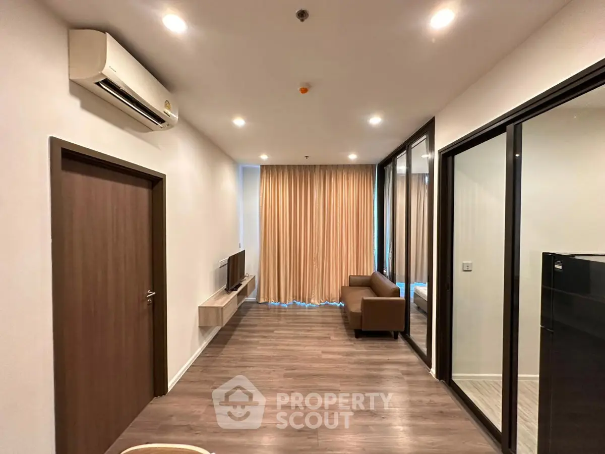 Modern living room with sleek design, featuring wooden flooring, air conditioning, and a cozy sofa.