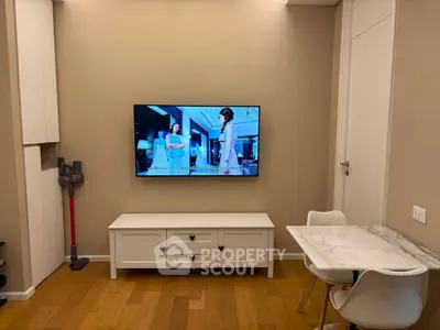 Cozy living room with wall-mounted TV, elegant white furniture, and wooden flooring.