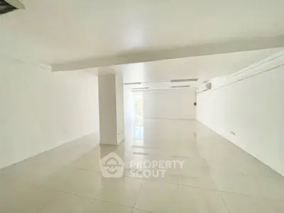 Spacious open-plan room with glossy tiled floors and white walls, ideal for customization.