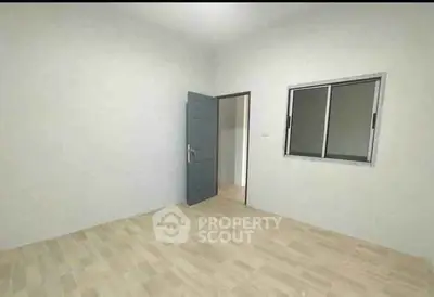 Spacious empty room with wooden flooring and a window, ideal for customization.