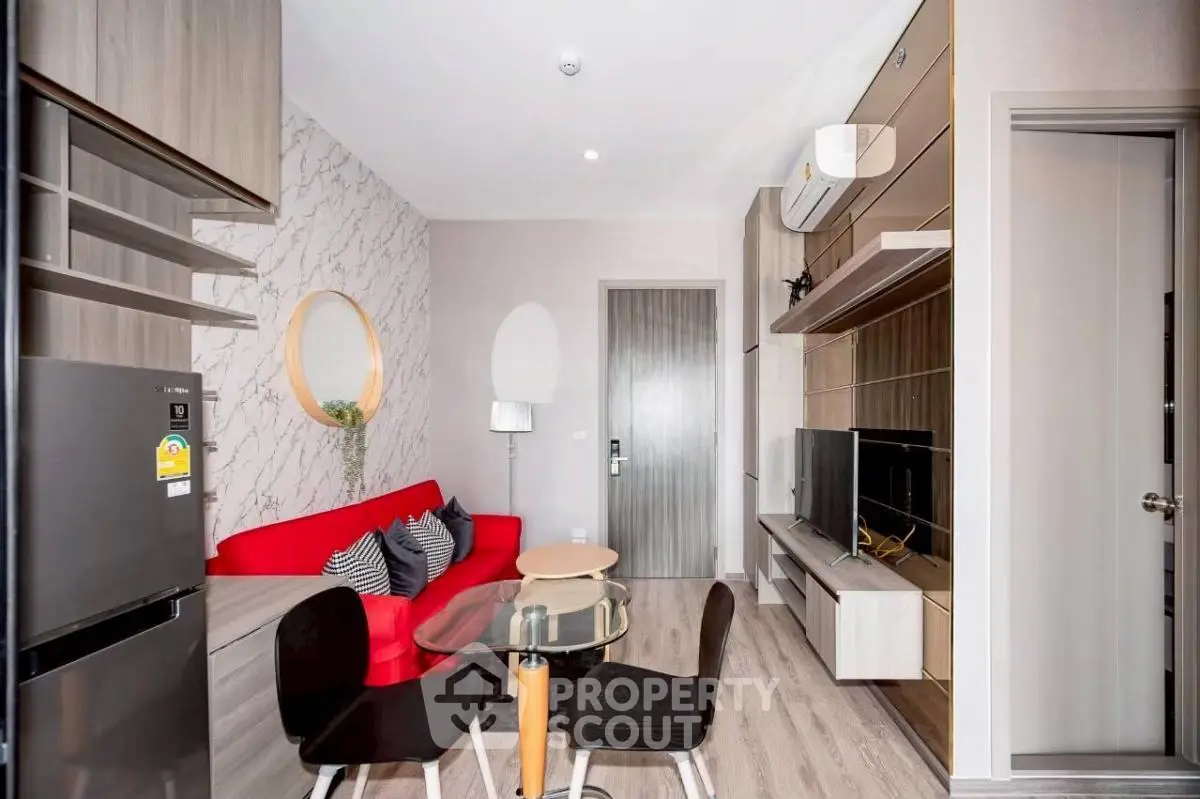 Modern living room with red sofa, TV unit, and dining area in stylish apartment.