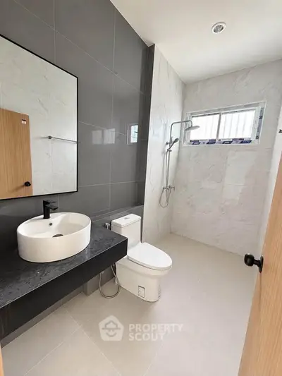 Modern bathroom with sleek design, featuring a stylish sink, toilet, and shower area with elegant tiles.