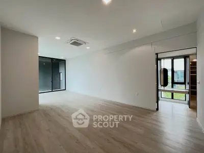Spacious modern living room with wooden flooring and large windows for natural light.