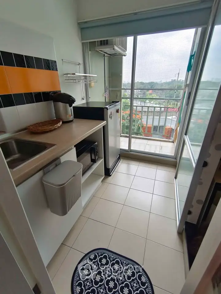 Modern kitchen with balcony view, featuring sleek appliances and stylish design in a compact space.
