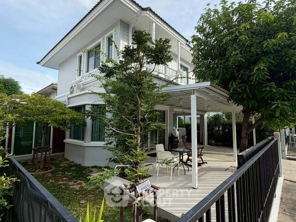 Charming two-story house with lush garden and spacious patio, perfect for outdoor relaxation.