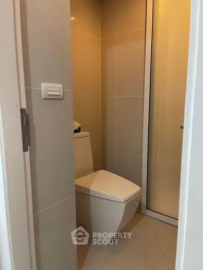 Compact modern bathroom with sleek toilet and neutral tiles