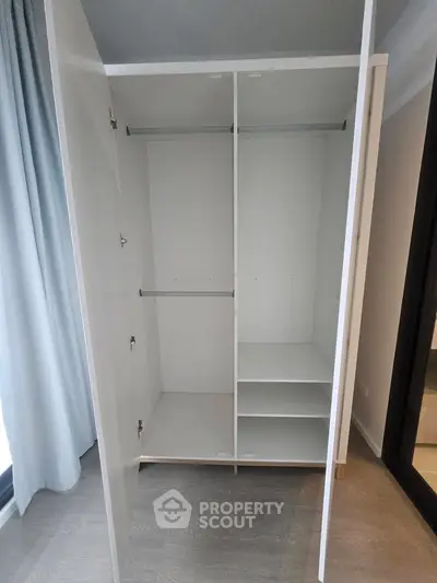 Spacious white wardrobe with hanging rods and shelves in modern interior.