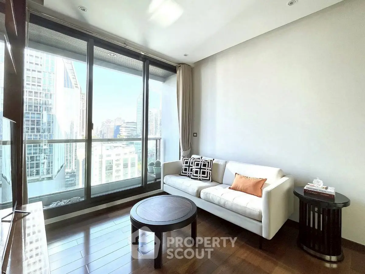 Modern living room with floor-to-ceiling windows and city view, featuring stylish furniture and wooden flooring.