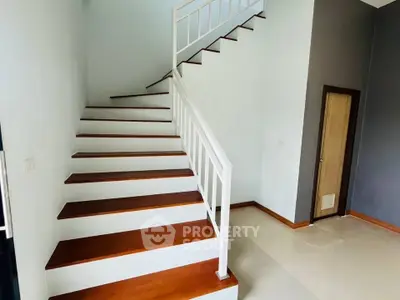 Modern staircase with wooden steps and white railing in a contemporary home interior.