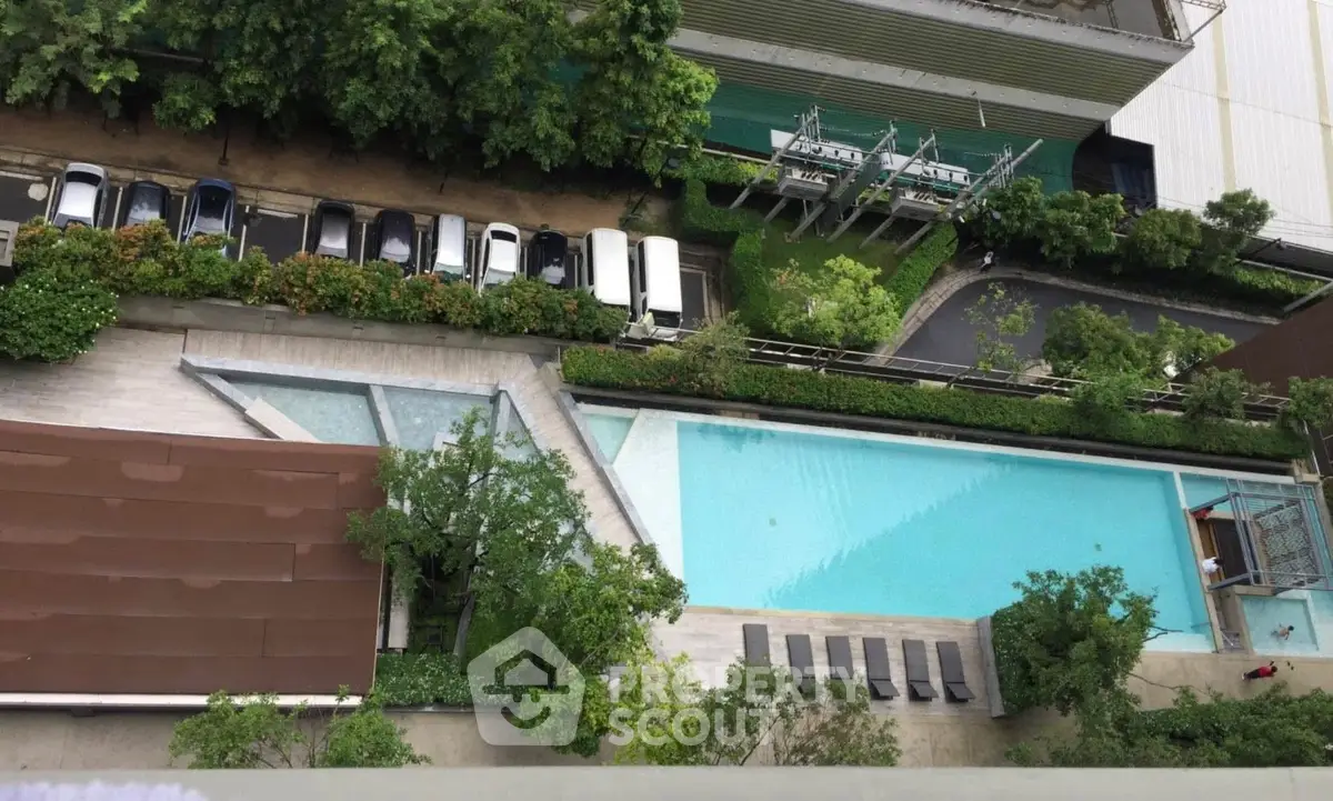 Stunning aerial view of modern swimming pool with lush greenery and parking area
