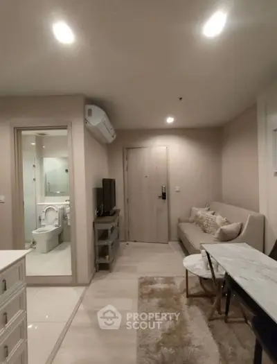 Modern living room with open view to bathroom, featuring sleek furniture and neutral tones.