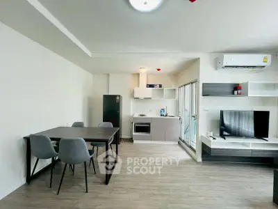 Modern open-plan living room with dining area and kitchen, featuring sleek furniture and appliances.