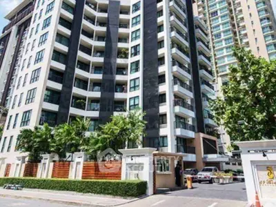 Modern high-rise building with lush greenery and secure entrance in urban setting.