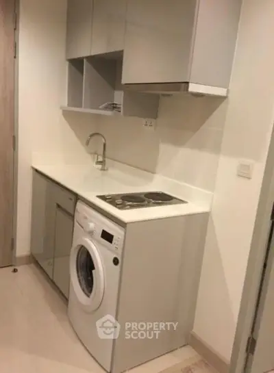 Compact kitchen with integrated washing machine and sleek cabinetry