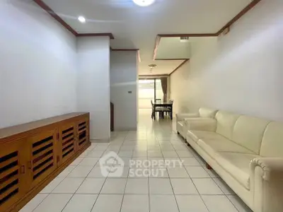 Spacious living room with elegant white sofa and dining area in the background.