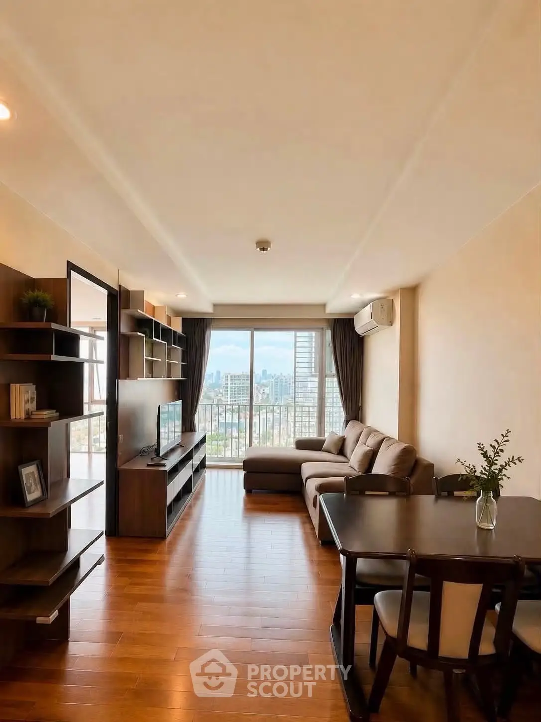 Spacious living room with city view, modern furniture, and wooden flooring in a high-rise apartment.