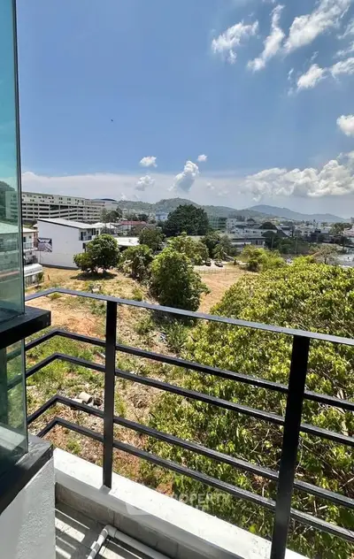 Stunning balcony view overlooking lush greenery and cityscape under a clear blue sky.