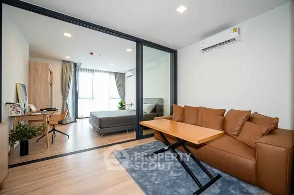 Modern studio apartment with glass partition, cozy living area, and stylish bedroom.
