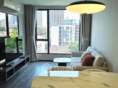 Modern living room with city view, featuring stylish furniture and large windows for natural light.