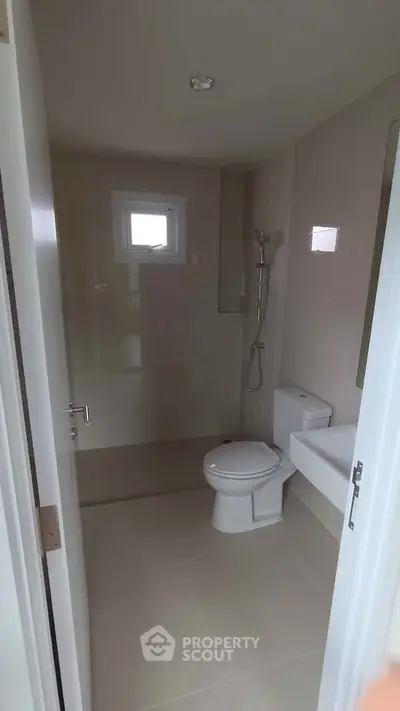 Modern bathroom with sleek fixtures and natural light from small windows.