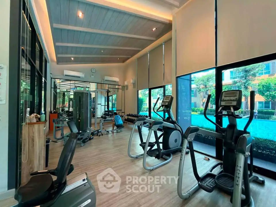 Modern gym with state-of-the-art equipment and large windows overlooking lush greenery.