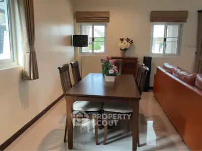 Charming dining area with elegant wooden table and chairs, adjacent to cozy living room with natural light.