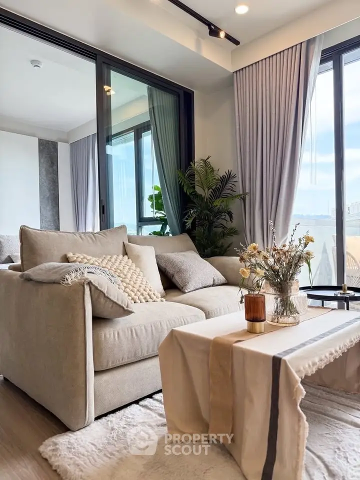 Stylish living room with cozy beige sofa, elegant decor, and large windows offering natural light and scenic views.