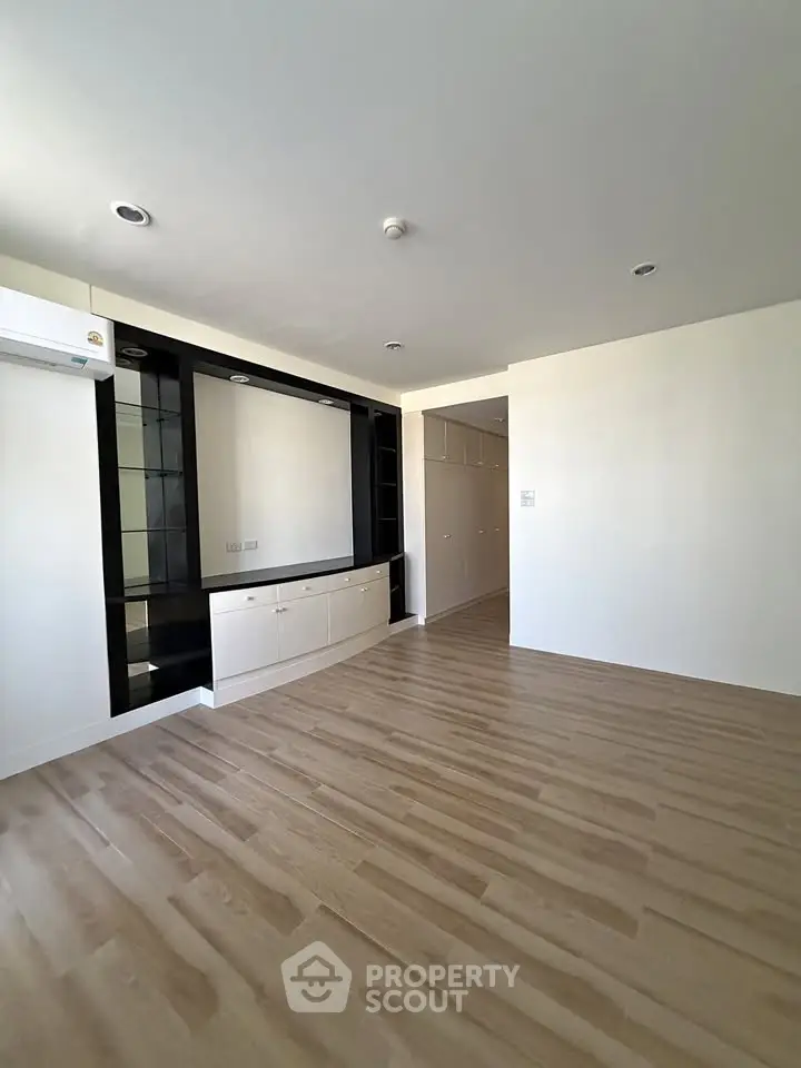 Spacious modern living room with sleek wooden flooring and built-in storage, perfect for stylish urban living.