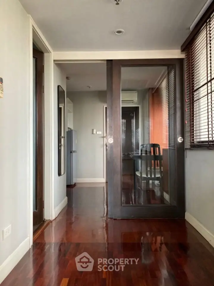 Spacious apartment hallway with wooden flooring and glass sliding doors