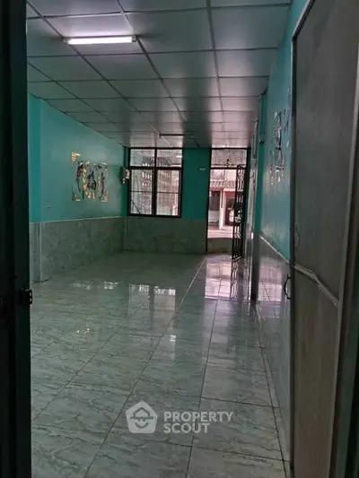 Spacious tiled room with teal walls and large windows, ideal for versatile use.