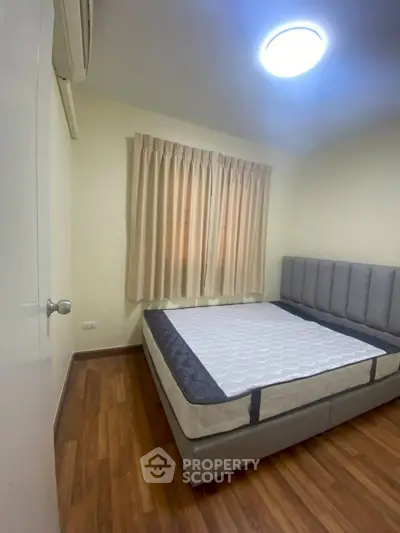 Cozy bedroom with wooden flooring and modern bed frame, perfect for a restful retreat.