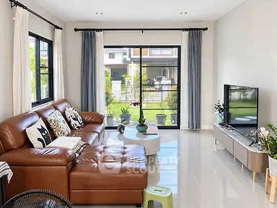 Spacious living room with modern leather sofa and large windows overlooking garden.