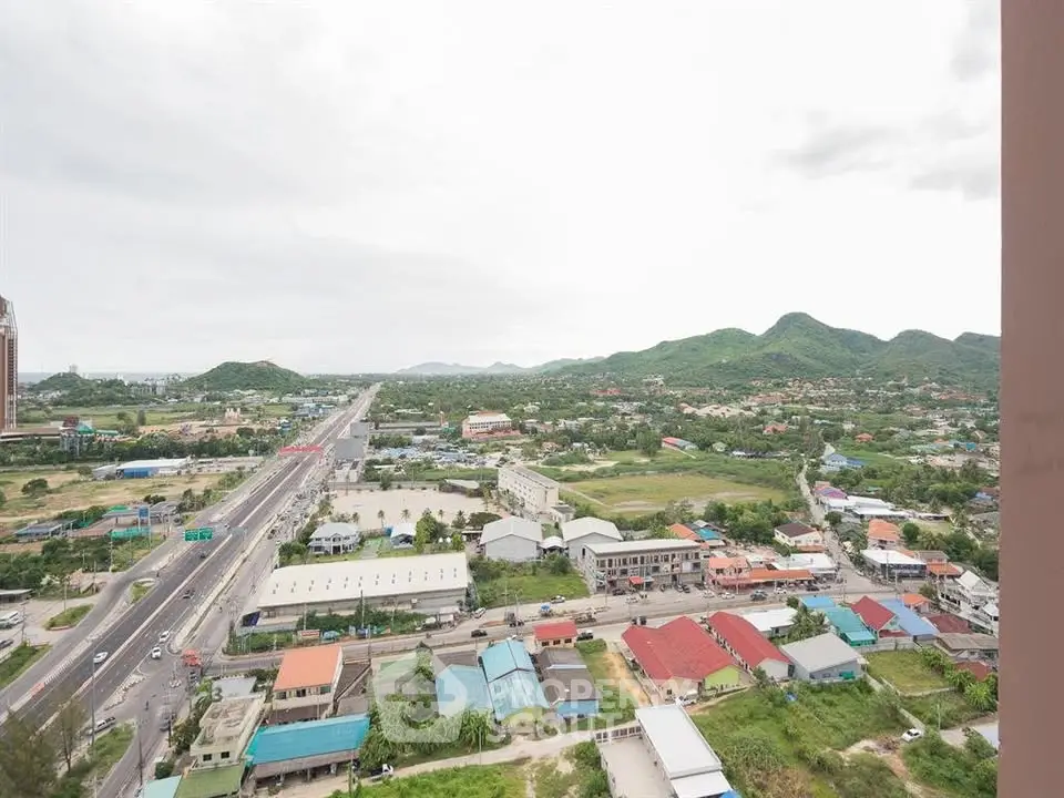 Stunning panoramic view from high-rise overlooking cityscape and lush green hills, perfect for urban living.