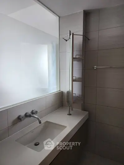 Modern bathroom with sleek sink and wall-mounted faucet, featuring neutral tile design.